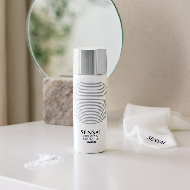 Sensai Silky Purifying Silk Peeling Powder 40 g enzympeeling ansikte i vit flaska med silverlock bredvid vitt pulver