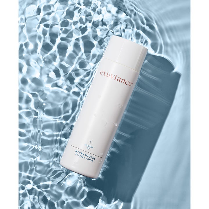 Exuviance HydraSoothe Refresh Toner 200 ml lugnande alkoholfri toner i vit flaska som vilar i krusande blått vatten