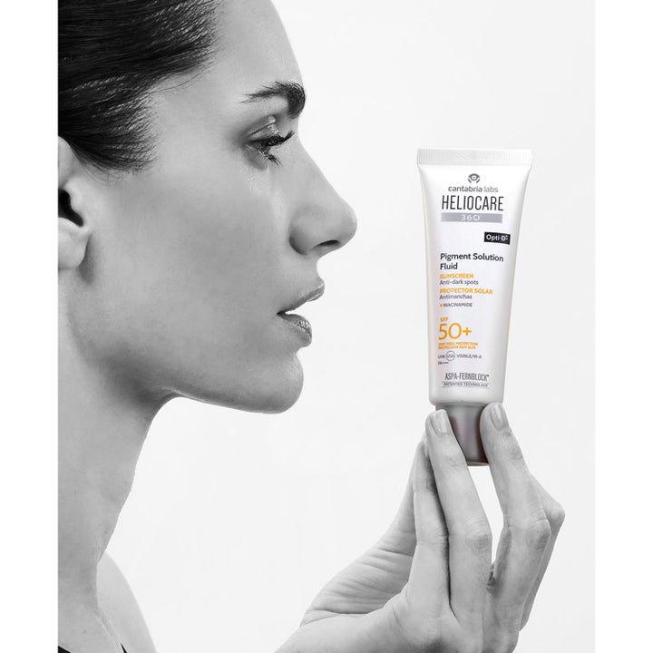 Heliocare Pigment Solution Fluid 50 ml bästa solskydd ansikte pigmentfläckar i vit tub som hålls av en kvinna