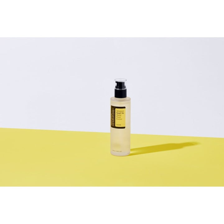 COSRX Advanced Snail 96 Essence Duo 2 x 100 ml återfuktande snigelslem i pumpflaska stående på gul yta.