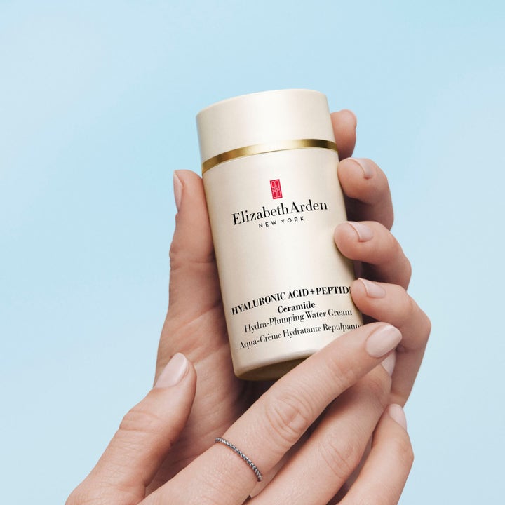 Elizabeth Arden Ceramide Hyaluronic Acid + Peptides Water Cream 50 ml återfuktande dagkräm i guldglänsande burk i händer.