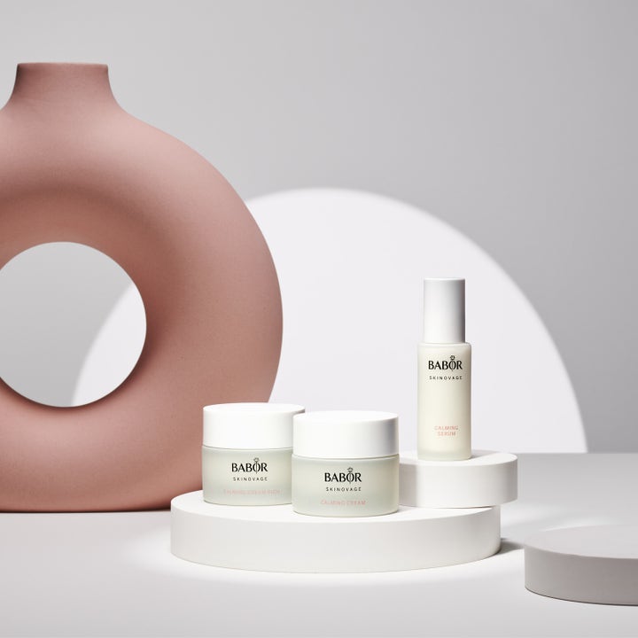 Babor Calming Serum 30 ml lugnande ansiktsserum i vit flaska på vita podier bredvid en rund rosa skulptur