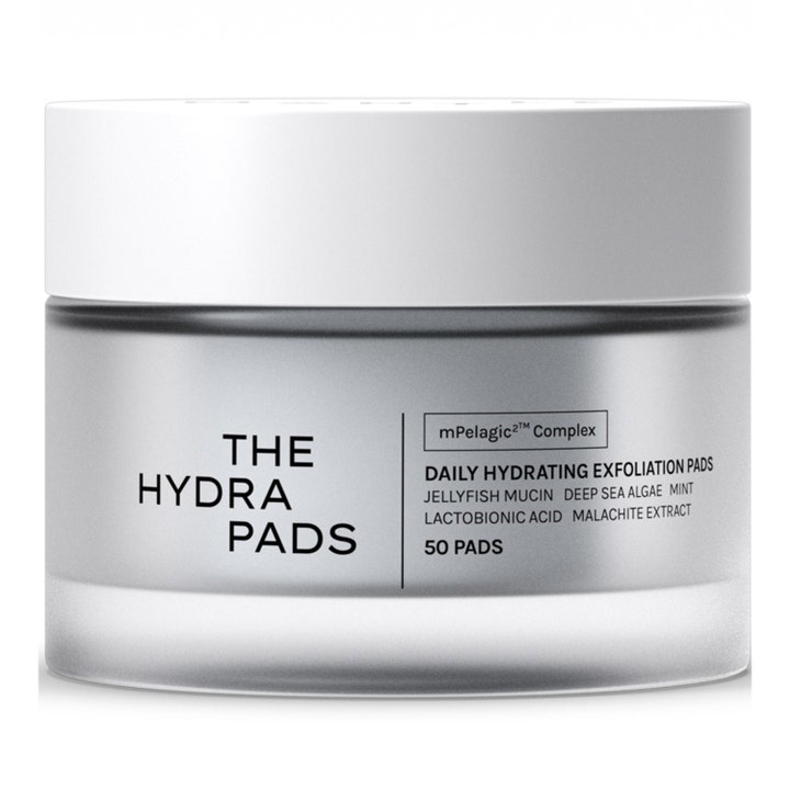 The Hydra Pads 50 st återfuktande exfolieringspads som ger lyster i en stilren frostad glasburk med vitt lock