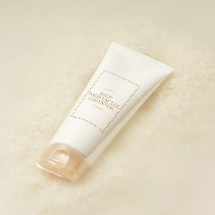 I'm from Rice Whip Facial Cleanser 150 ml mjukgörande ansiktsrengöring i vit tub som vilar på en bädd av ris.