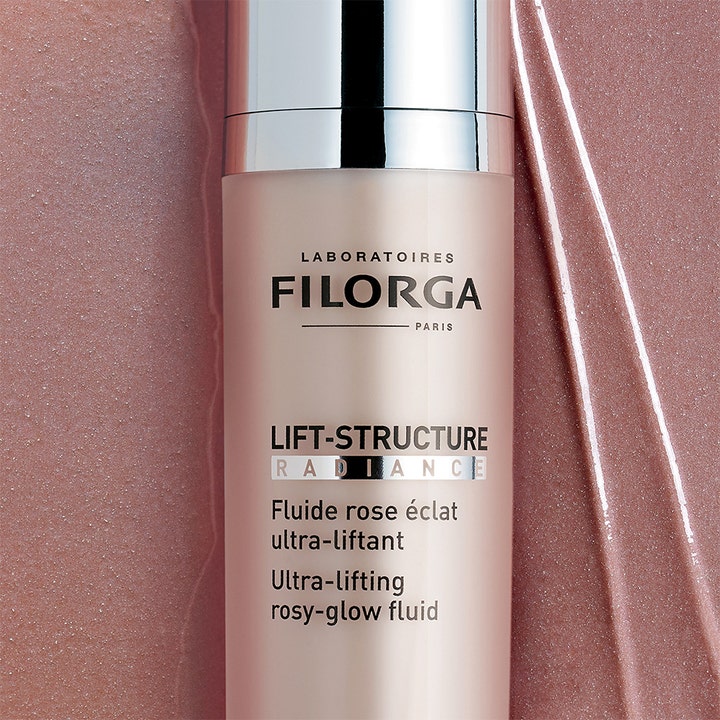 Filorga Lift-Structure Radiance 50 ml lystergivande dagkräm i flaska med silverlock mot en rosa skimrande textur