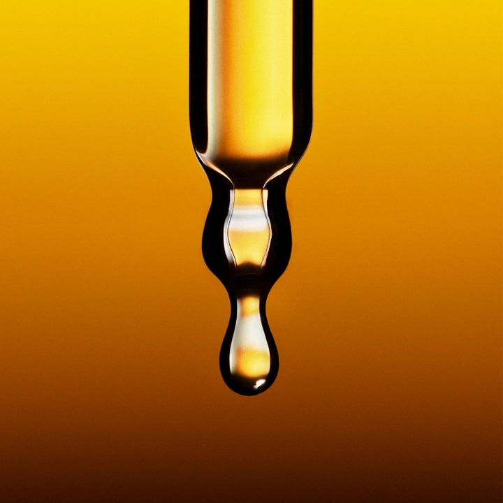 Jorgobé Antioxidant Self-Tan Drops 30 ml ger lyster med en gyllene droppe från en pipett mot varm bakgrund