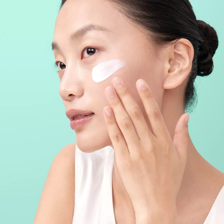 Klairs All-day Airy Mineral Sunscreen 60 g solskydd för ansiktet som kvinna applicerar med vit kräm på kinden