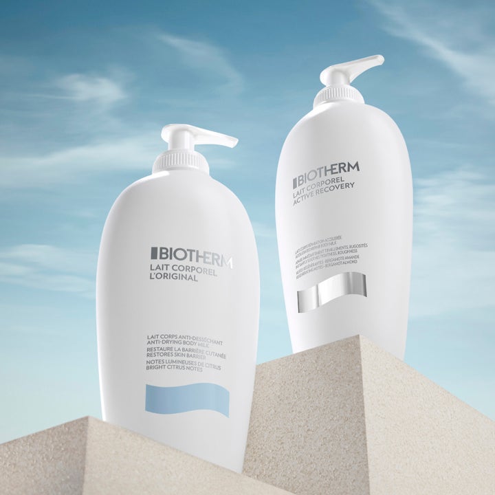 Biotherm Lait Corporel Active Recovery 400 ml återfuktande bodylotion i vita pumpflaskor på stenblock mot blå himmel.
