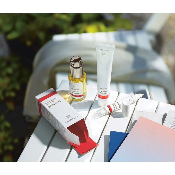 Dr. Hauschka Hand Cream 50 ml återfuktande handkräm i vit tub på ett vitt träbord i en solig trädgårdsmiljö.