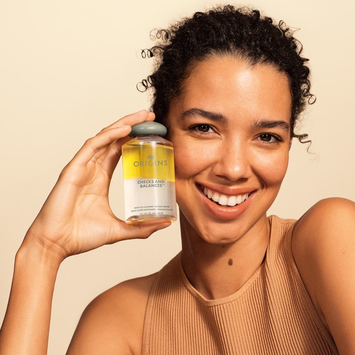 Origins Checks & Balances Milky Oil Cleanser 150 ml milky oil cleanser ansikte som hålls av en leende kvinna