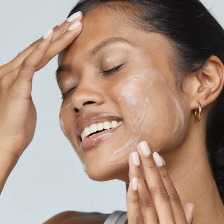 Dermalogica Sensitive Skin Rescue Kit lugnande ansiktsvård där kvinna applicerar en vit krämig produkt på huden.