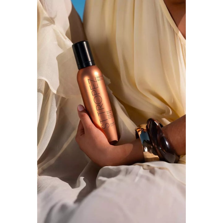 St.Tropez Instant Glow Body Bronzing Mousse 200 ml ger lyster i en bronsfärgad flaska som hålls i handen.