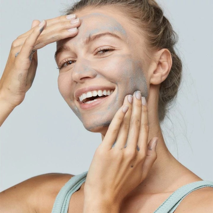 Dermalogica Daily Superfoliant 13 g peeling som en leende kvinna applicerar i ansiktet för en jämnare hudton