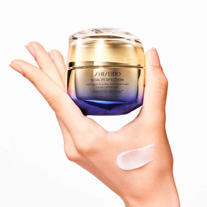 Shiseido Vital Perfection Advanced Day Cream 50 ml uppstramande dagkräm i guld och lila burk med krämig textur på handen