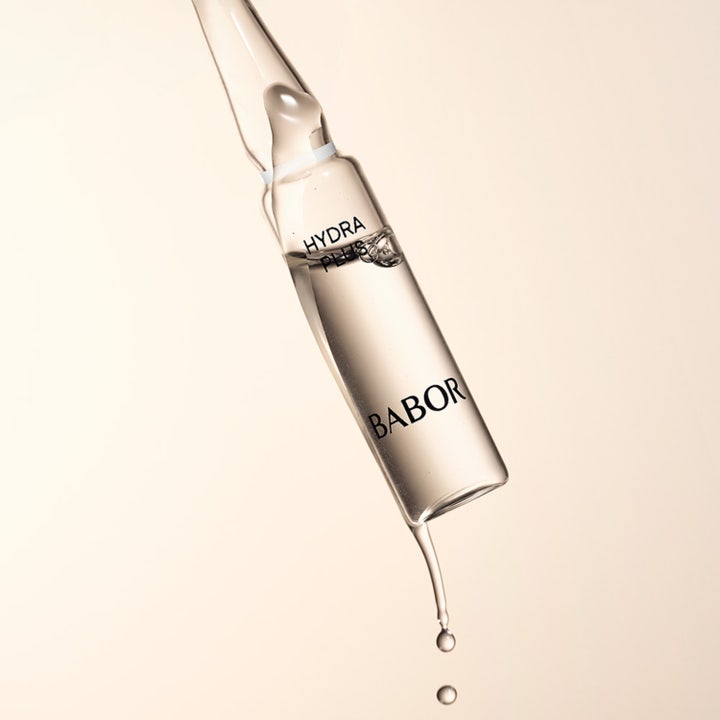 Babor Ampoule Hydra Plus 14 ml hyaluronsyra ampull ansiktsserum som droppar mot en beige bakgrund