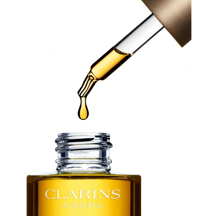 Clarins Santal Face Treatment Oil 30 ml lugnande ansiktsolja med en glaspipett som droppar gyllene olja.