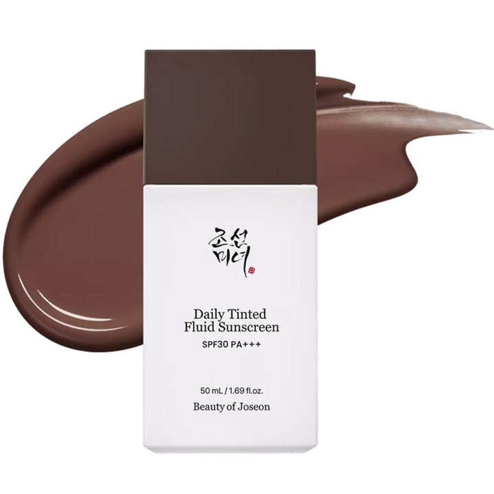 Beauty of Joseon Daily Tinted Fluid Sunscreen 50 ml skyddande solkräm i vit flaska framför mörkbrun krämig textur.