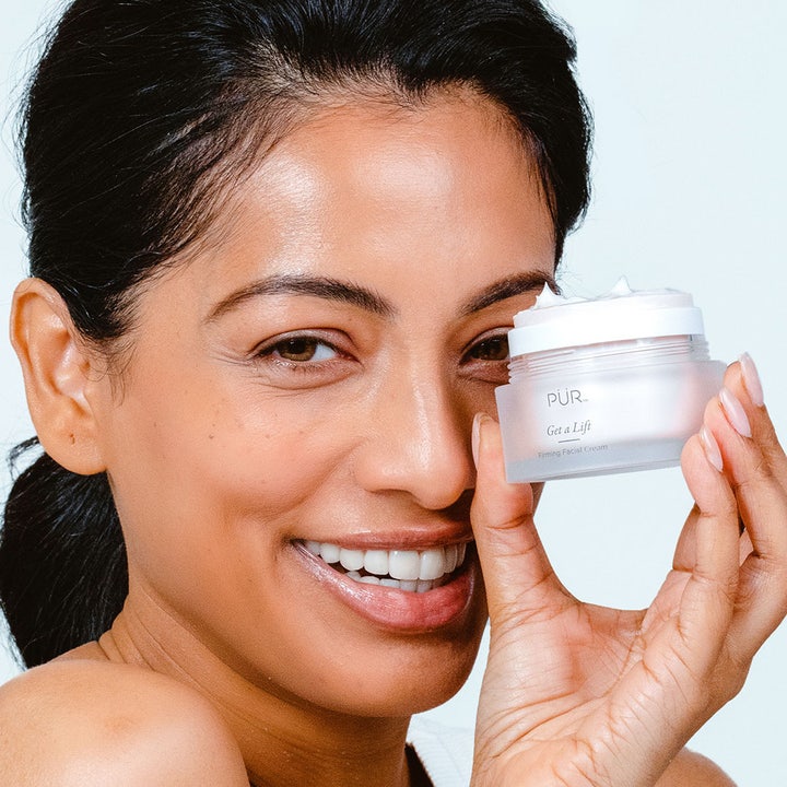PÜR Get A Lift Cream 50 ml uppstramande ansiktskräm i frostad glasburk som visas upp av en leende kvinna.