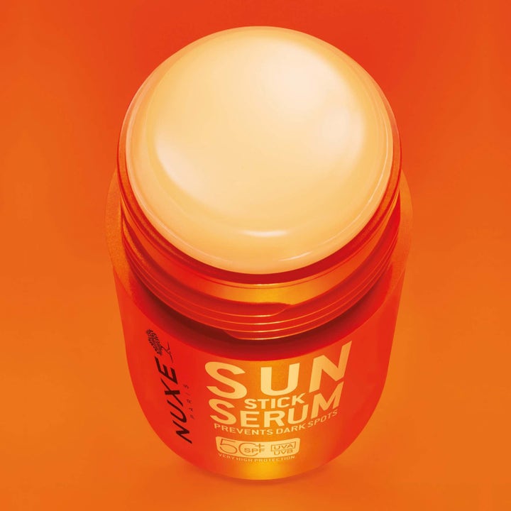 Nuxe Sun Stick Serum 25 g solkräm för ansiktet motverkar mörka fläckar i en orange hylsa med krämigt SPF 50 stift.