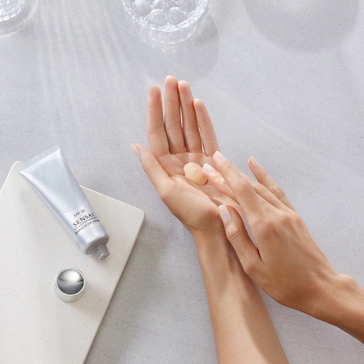 Sensai Cellular Performance Advanced Day Cream 50 ml dagkräm med spf 30 i silverfärgad tub med mjuk textur på händer.
