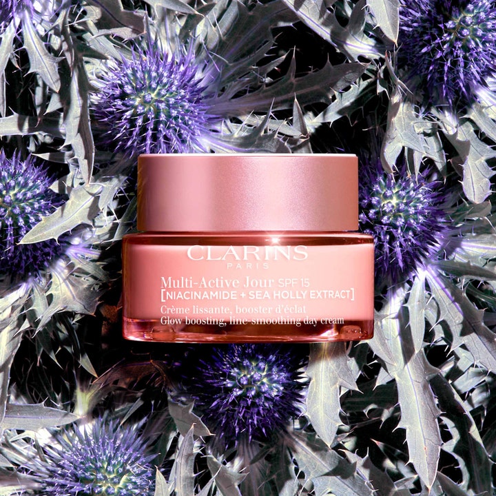 Clarins Multi-Active Jour 50 ml niacinamide ansiktskräm för lyster i rosa glasburk bland lila martorn.