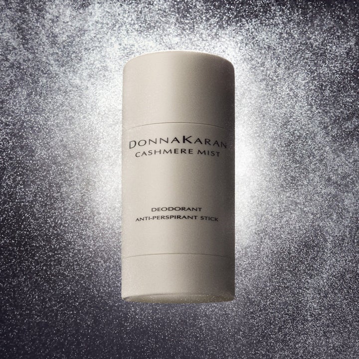 DKNY Cashmere Mist Anti-Perspirant Stick i beige hylsa som ger fräschör mot en glittrande mörk bakgrund.