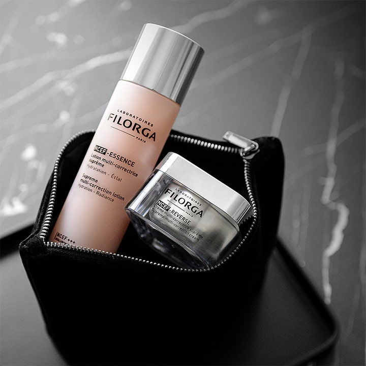 Filorga NCEF-Essence 150 ml lystergivande filorga essence ansiktslotion i rosa flaska placerad i en svart necessär.