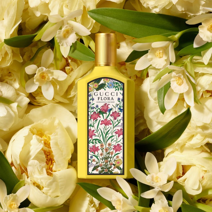 Gucci Flora Gorgeous Orchid 50 ml blommig parfym i gul flaska placerad i en bädd av ljusa blommor
