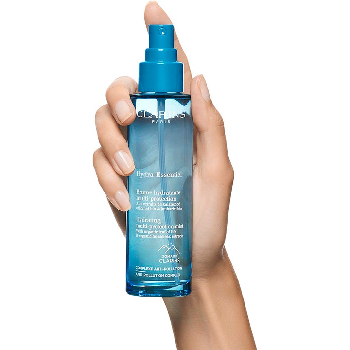 Clarins Hydra-Essentiel 75 ml återfuktande ansiktsmist med anti-pollution i en blå transparent flaska som hålls i en hand