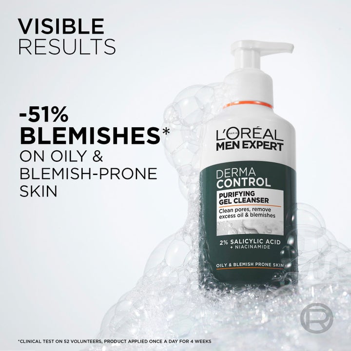 L'Oréal Paris Men Expert Derma Control 310 ml ansiktsrengöring i vit pumpflaska omgiven av lödder mot orenheter.
