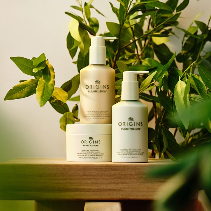 Origins Plantfusion Softening Hand & Body Lotion 75 ml är en botanisk kroppslotion för torr hud bland gröna blad.