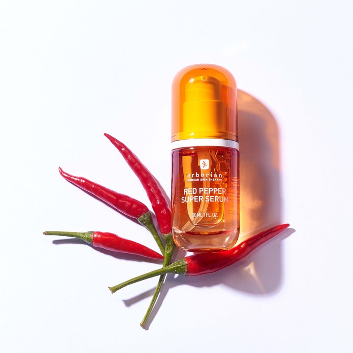 Erborian Red Pepper Super Serum 30 ml lystergivande ansiktsserum i orange flaska omgiven av röda chilipepparfrukter
