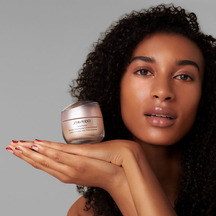 Shiseido Benefiance Wrinkle Smoothing Enriched Cream 50 ml rynkreducerande kräm i beige burk som hålls av en kvinna.