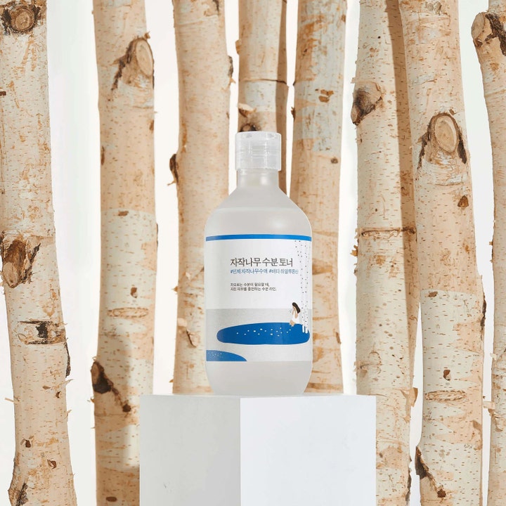 Round Lab Birch Juice Moisturizing Toner 300 ml återfuktande björksav ansiktsvatten i flaska omgiven av björkstammar
