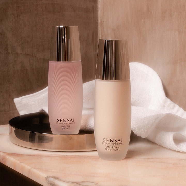Sensai Cellular Performance Emulsion III 100 ml lyxemulsion i frostad flaska med silverlock bredvid en vit handduk