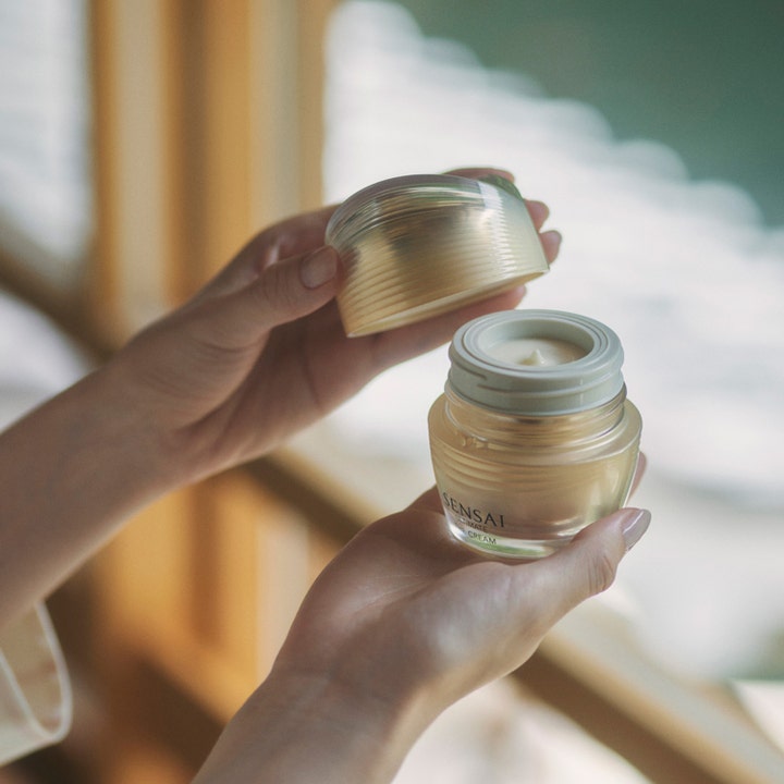 Sensai Ultimate The Cream 40 ml anti-age kräm för fastare hud i en lyxig guldfärgad glasburk som hålls i händerna