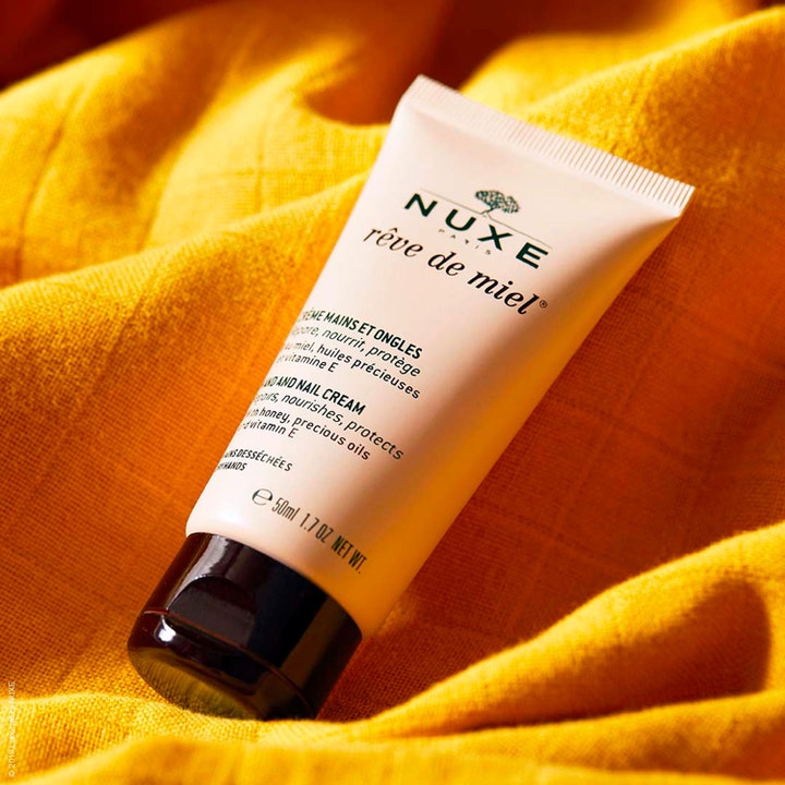 Nuxe Rêve de Miel Hand and Nail Cream 50 ml reparerande hand och nagelkräm vitamin e i beige tub på gult tyg