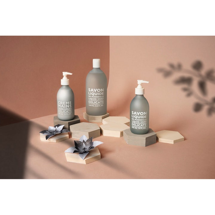 Compagnie de Provence Liquid Marseille Soap Delicate 300 ml fransk flytande tvål i grå glasflaska på hexagonala träblock.