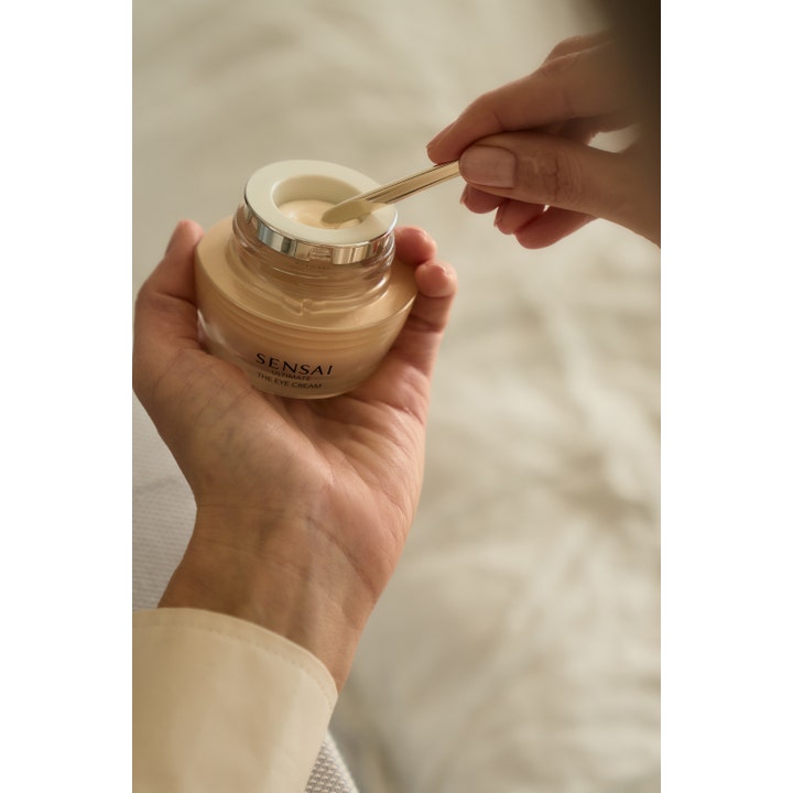 Sensai Ultimate The Eye Cream 15 ml lyxig ögonkräm mot påsar i en guldtonad glasburk som appliceras med guldspatel.