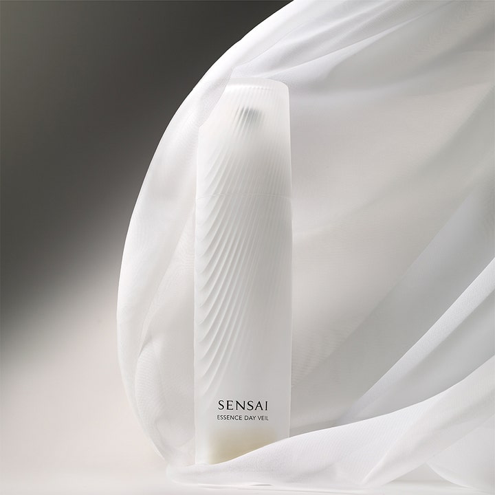 Sensai Essence Day Veil 40 ml fuktgivande primer och anti-aging dagkräm i vit flaska omgiven av skirt tyg