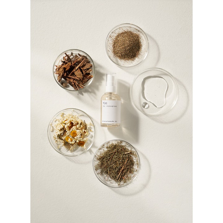 Mixsoon Calming Boosting Mist 50 ml koreansk lugnande ansiktsspray omgiven av örter och torkad kamomill i glasskålar.