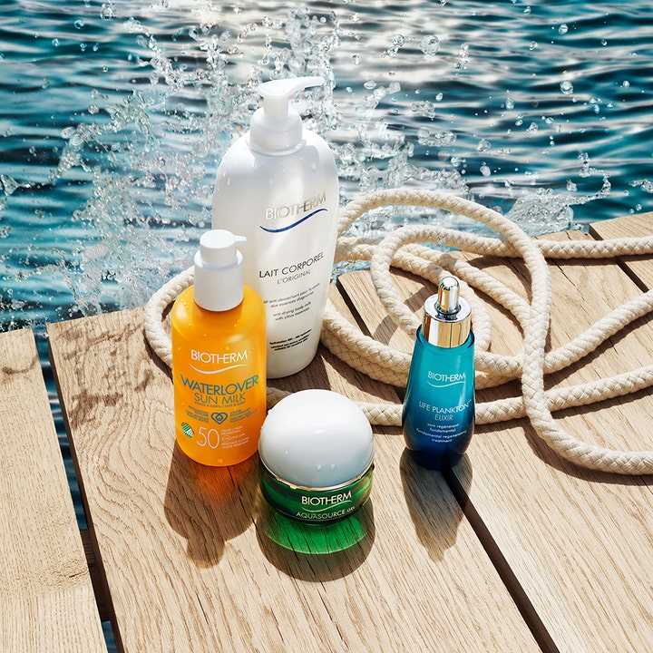 Biotherm Waterlover Sun Milk 200 ml solmjölk strand ger fukt i gul flaska på en träbrygga vid glittrande vatten
