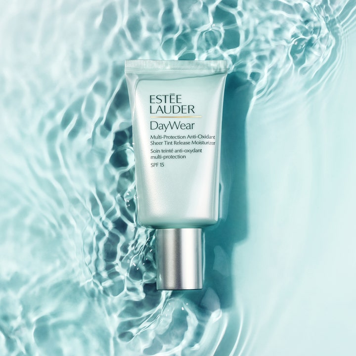 Estée Lauder DayWear Sheer Tint Moisturizer 50 ml i ljusgrön tub mot en bakgrund av böljande blått vatten