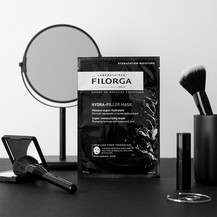 Filorga Hydra-Filler Mask 23 g återfuktande mask med hyaluronsyra i svart sachet intill spegel och borstar.