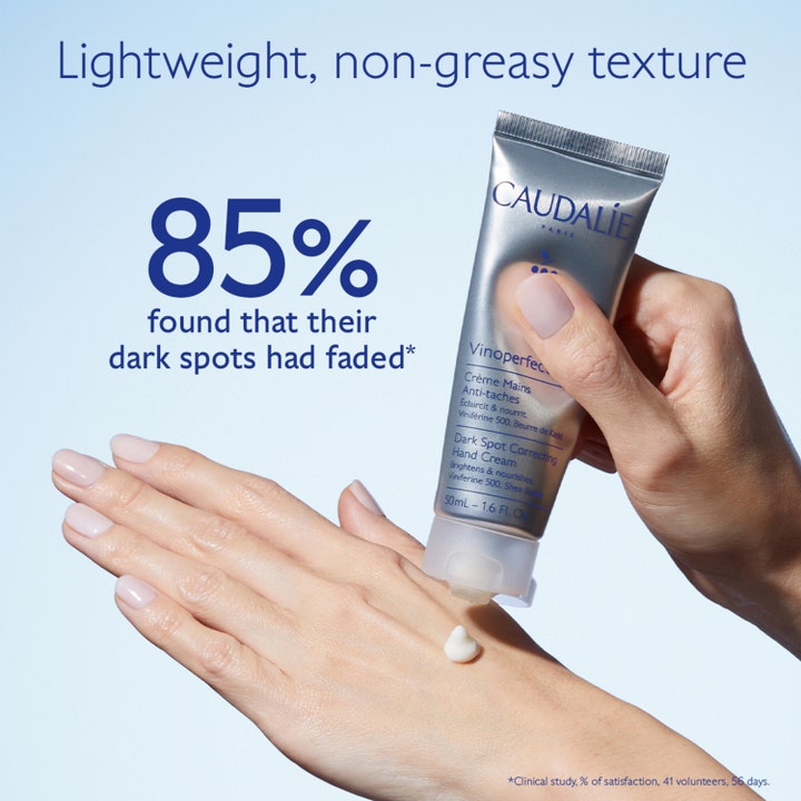 Caudalie Vinoperfect Dark Spot Correcting Hand Cream 50 ml mot mörka fläckar visar vit kräm på hand och en silvertub.