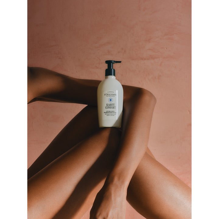 L'Occitane Shea Butter Body Lotion 240 ml intensivt närande lotion på en pumpflaska mot en hudnära bakgrund
