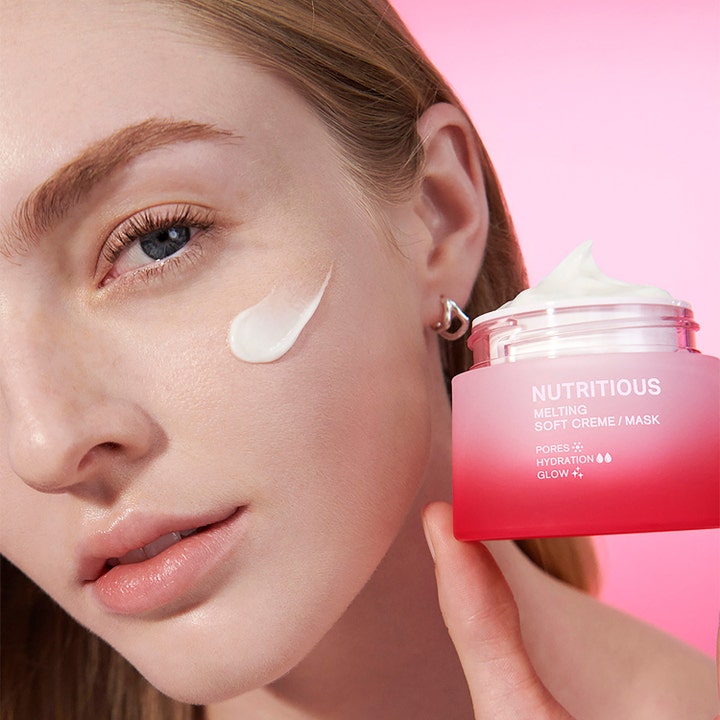 Estée Lauder Nutritious Melting Soft Cream And Mask 50 ml i rosa burk applicerad på kind för lyster.
