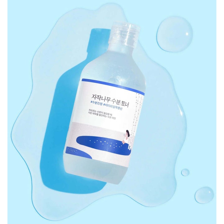 Round Lab Birch Juice Moisturizing Toner 300 ml återfuktande björksav ansiktsvatten i klar flaska på blå vattenbakgrund.