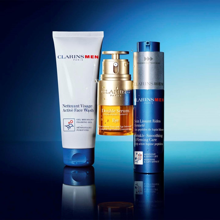 Clarins Men Wrinkle-Smoothing & Firming Care 50 ml ger fasthet i en blå pumpflaska bredvid ansiktstvätt och serum.