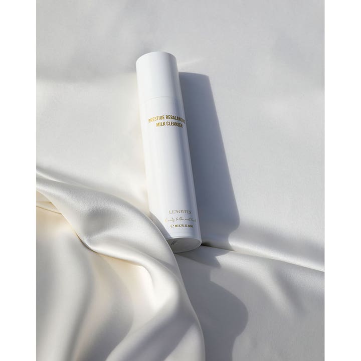Lenoites Prestige Rebalancing Milk Cleanser 200 ml balanserade rengöringsmjölk i vit flaska på vitt sidentyg.